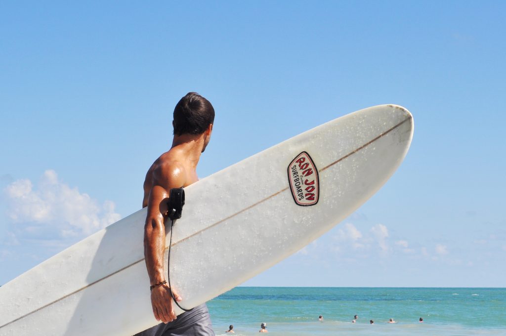 Surfer mit Brett in der Hand und Blick auf Strand von Florida